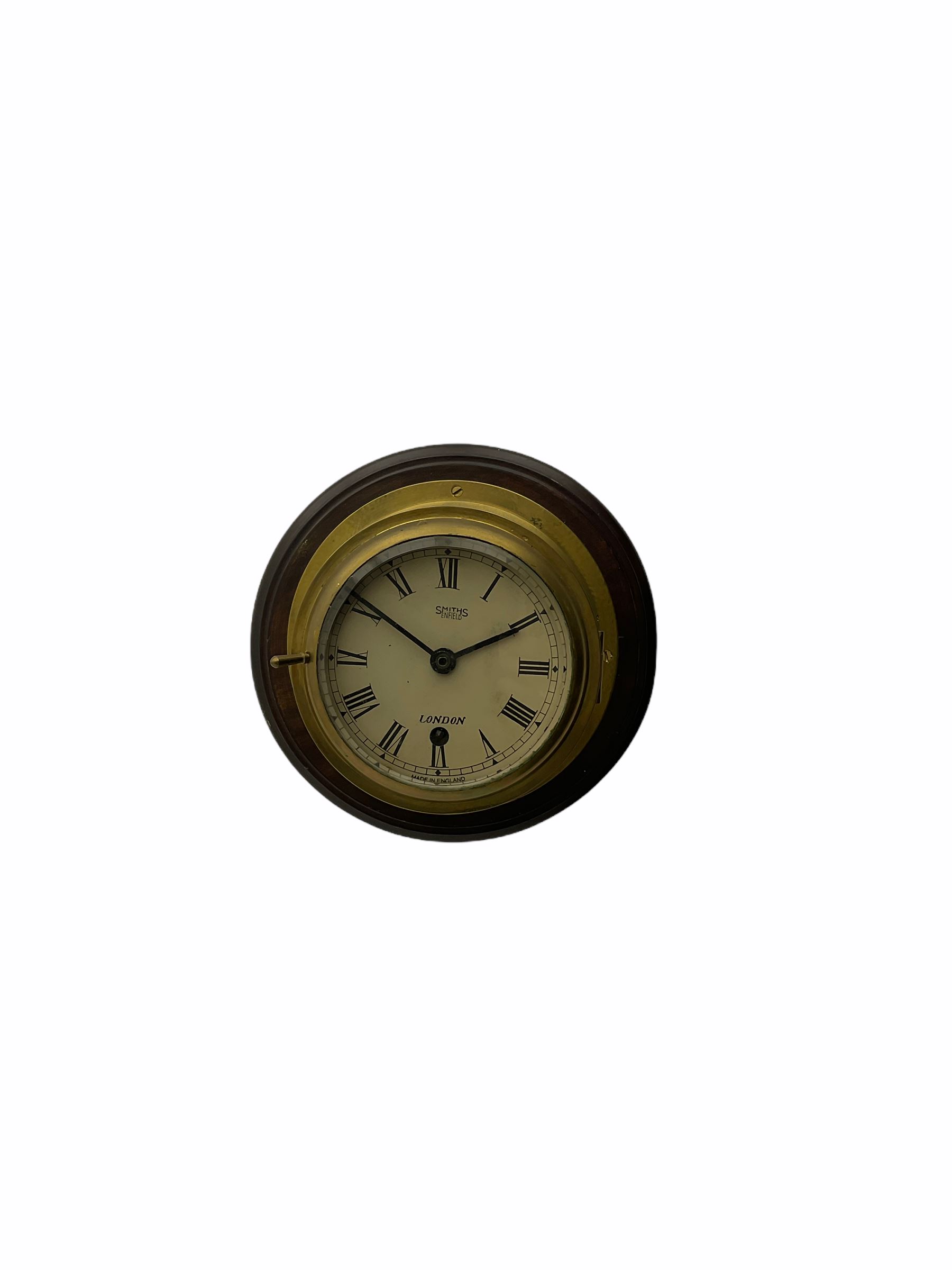 20th century brass cased bulkhead clock mounted on a circular mahogany