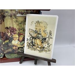 Two ceramic Hummel postcards by Goebel, both displayed on wooden easels, together nine Hummel eggs, set of four Hummel School Days plates, on wooden hanging rack, Goebel Collectors Club Member plaque etc