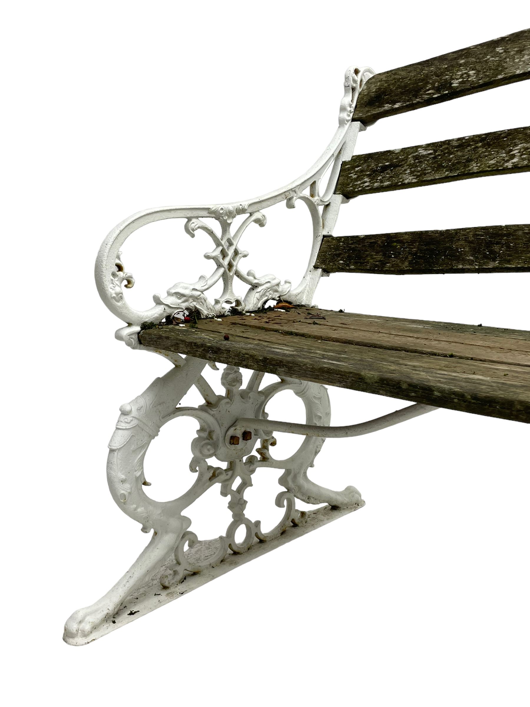 Late 19th century white painted cast iron and wood slatted garden bench, the bench ends in the form of S-scroll mythical beasts with paw feet, central cartouche surrounded by extending trailing foliage, the back slats divided by scroll cast splats, central seat support 