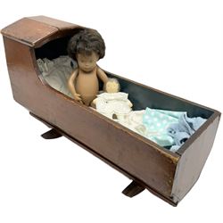 Victorian stained pine rocking dolls crib, with hood to one end, together with a jointed vinyl doll, crib H33cm L53.5cm