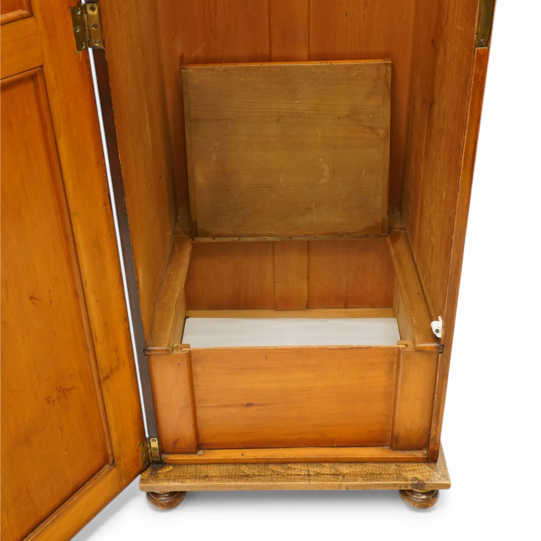 Late 19th century Arts & Crafts stained pine single hall wardrobe, single panelled door with brass fittings enclosing sliding tray to top with hanging rail and hooks, hinged box seat to base, on compressed bun feet