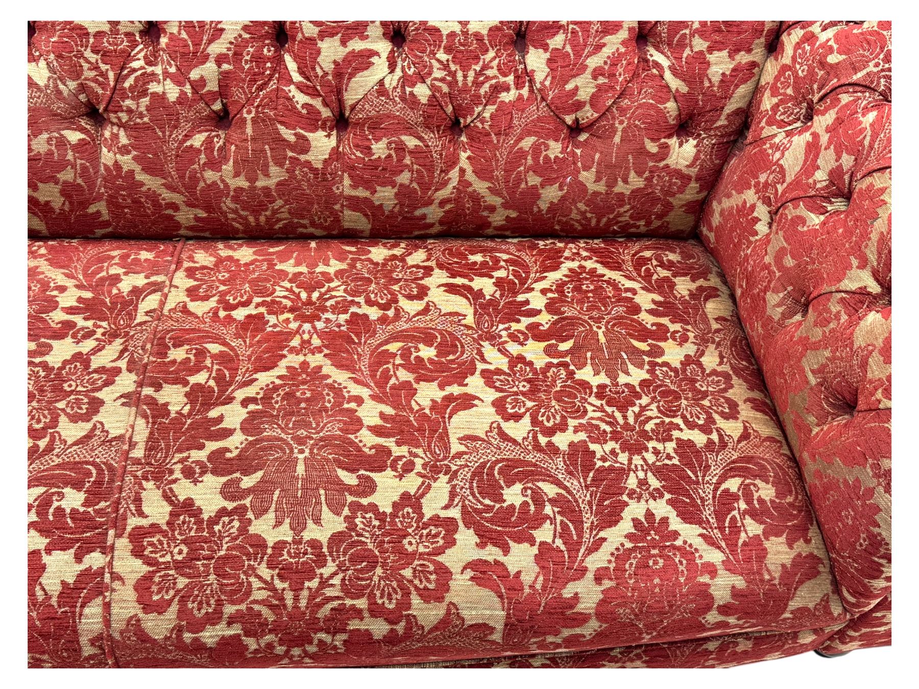 Late 20th century upholstered Chesterfield sofa, in red damask floral fabric, with deep buttoned back and arms, scrolled arms at equal height to back, on turned front supports