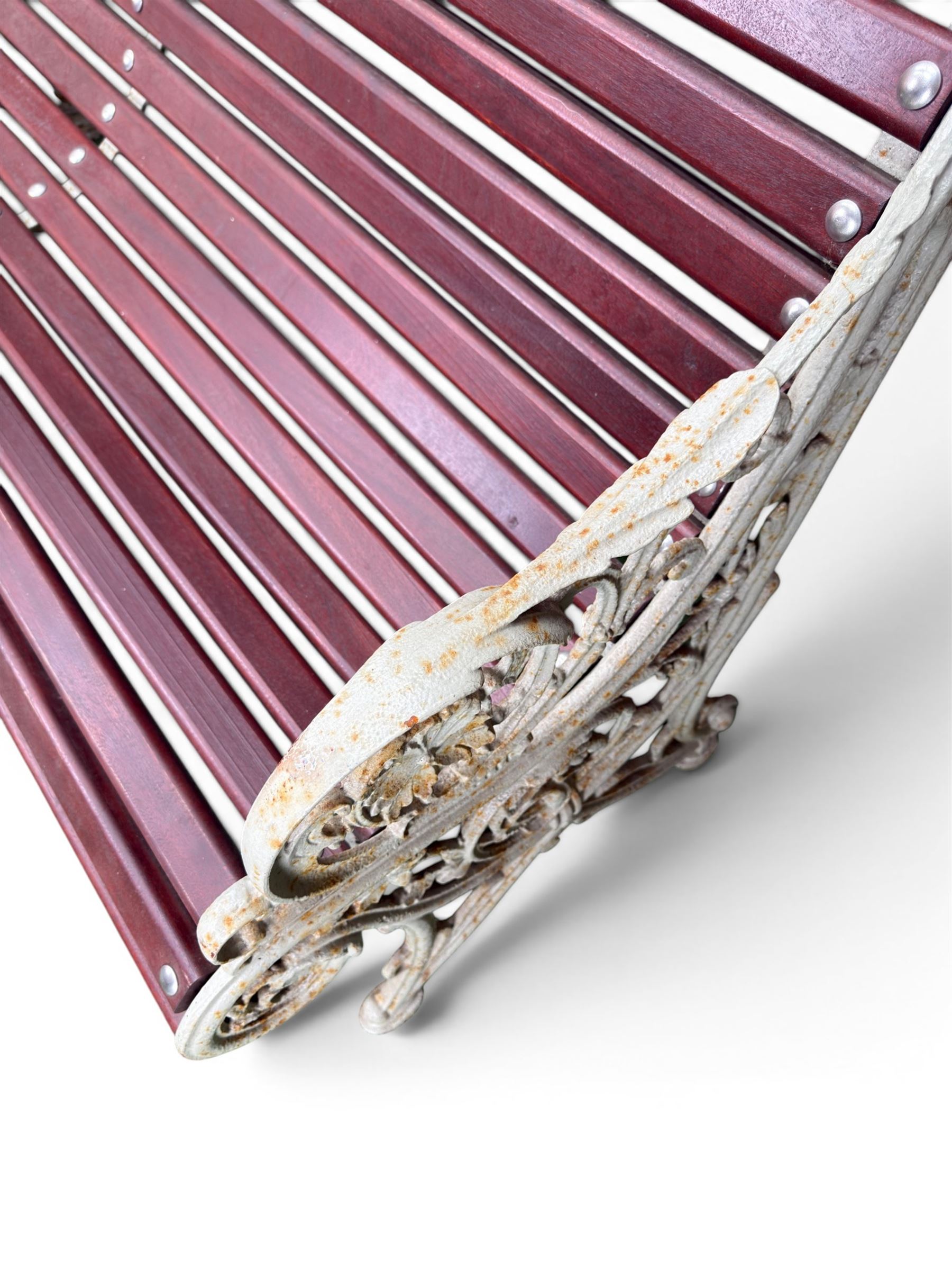 Large late Victorian cast iron garden bench, serpentine form with scroll back and seat, slatted with mahogany stained Sapele