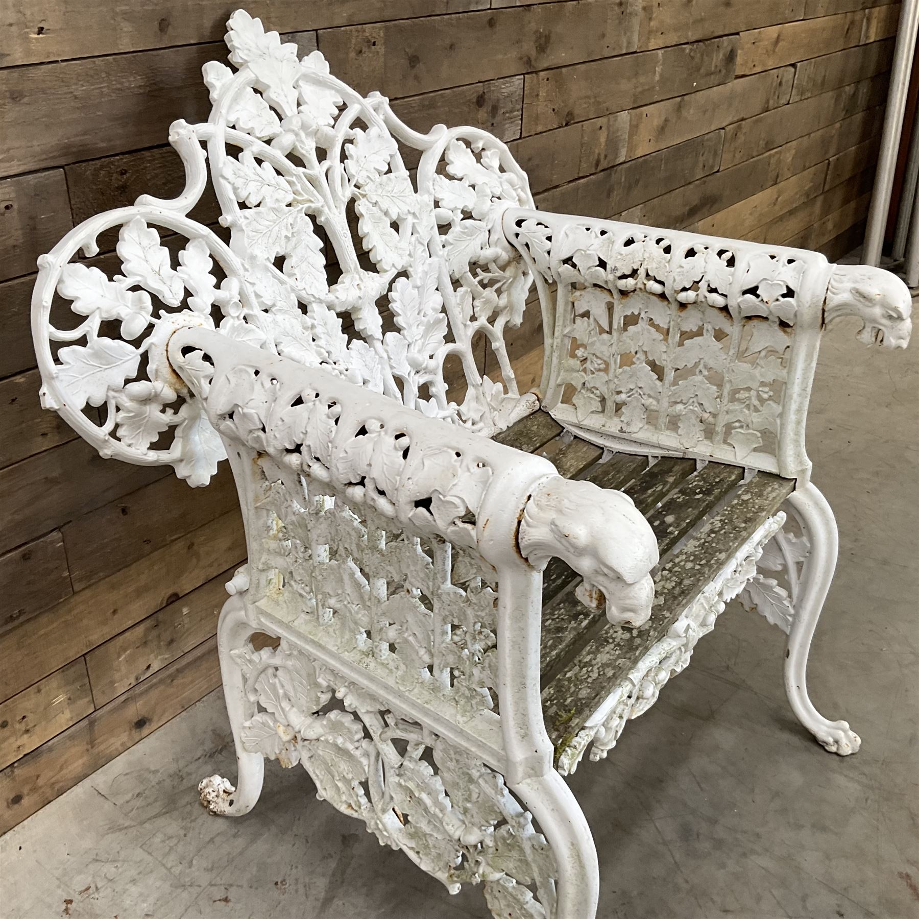 20th century Coalbrookdale design cast iron oak leaf and acorn armchair, white painted cast iron frame with slatted wooden seat, the pierced and shaped back decorated with scrolling oak branches and leafage, flanked by dog mask arm terminals over cabriole supports with paw feet