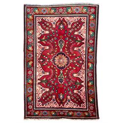 Persian Azerbaijan crimson ground rug, the field decorated with central floral motif and surrounded by trailing floral branches, enclosed within a shaped outer band with further floral decoration, the border with repeating flower heads, geometric guard stripes 