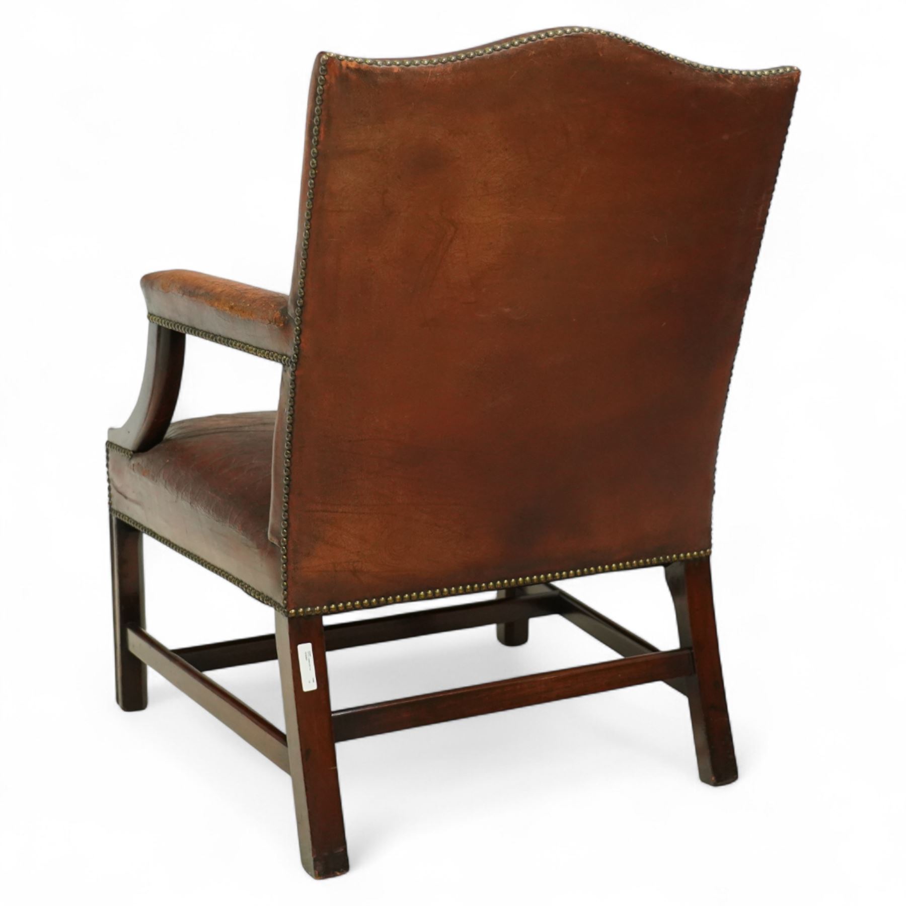 Early 20th-century Gainsborough-style library armchair, padded back, arms, and seat, brass button upholstered in brown leather, on square tapered front legs united by a stretcher 