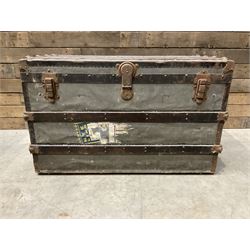 Early 20th century wood and metal bound zinc travelling trunk, hinged top with three clasps, decorated with period luggage labels