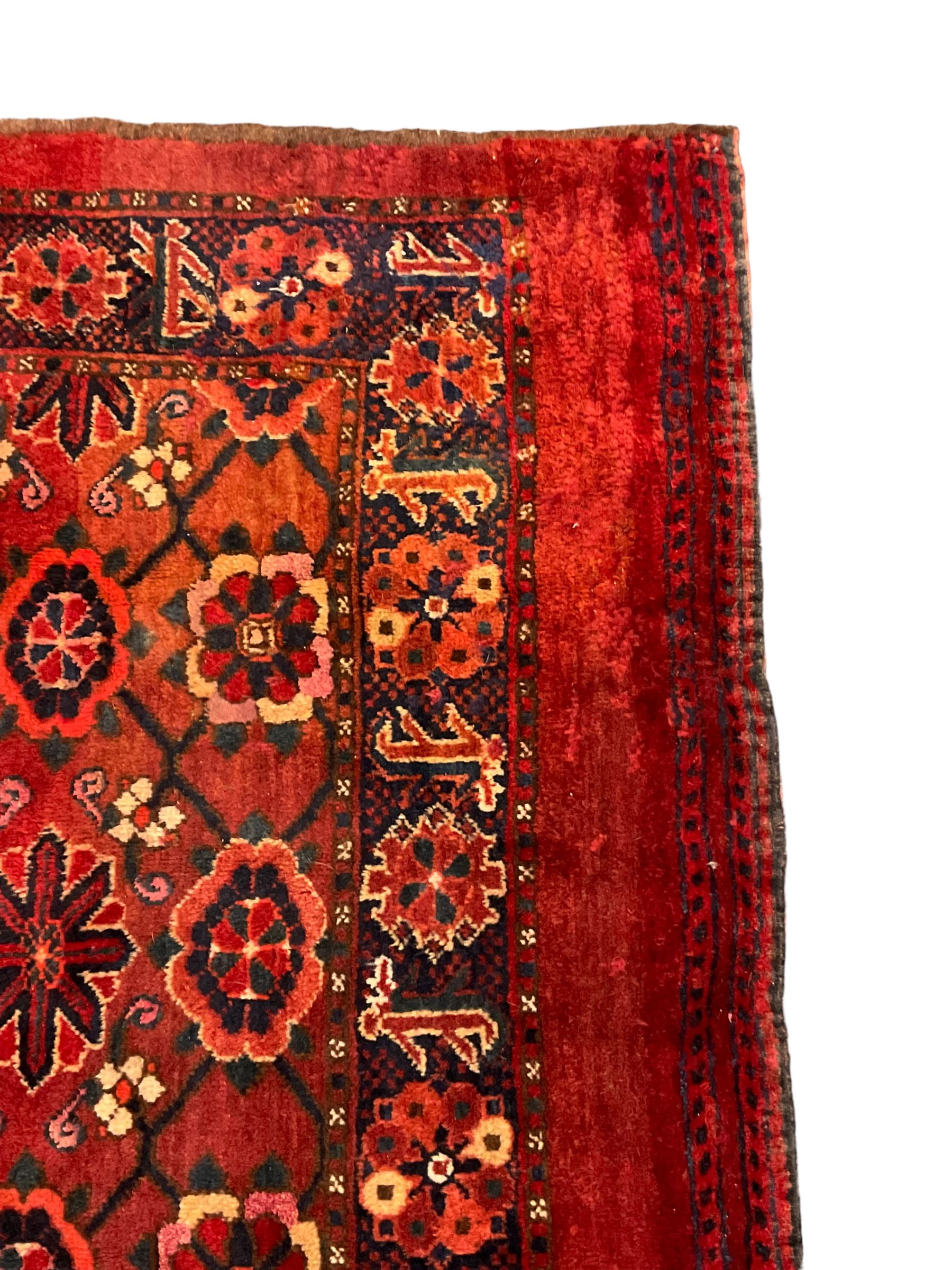 Persian red ground rug, the field decorated with lattice pattern and flowerhead, repeating border decorated with flower heads and leaf motifs