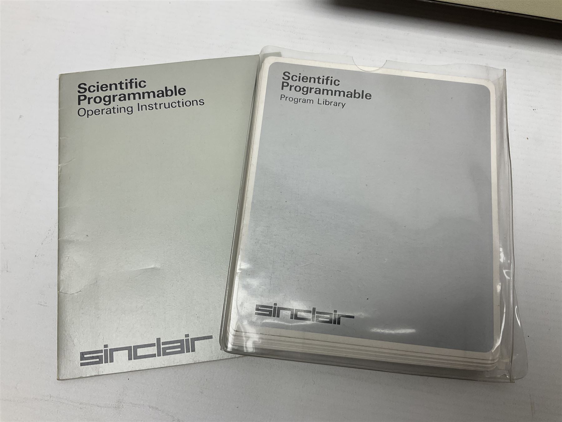 Four 1970s Sinclair electronic calculators - Cambridge in hard case with booklet; Scientific Programmable with Program Library and booklet; Scientific in hard case; and Oxford 300 in soft case with booklet; together with Texas PC-100 SR56 programmable slide-rule calculator on base station with readout, two booklets, keys and cover, serial no.9103093