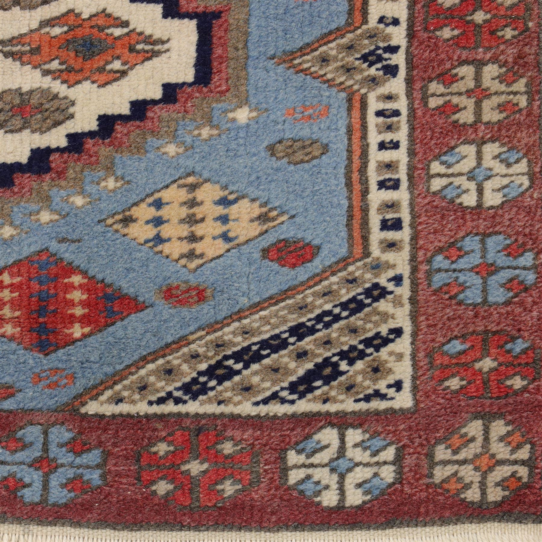 Caucasian Kazak hand-knotted rug, pale blue main field with large geometric medallions in a vertical arrangement and angular tribal motifs within a rosette and geometric border, cotton fringe end, 68x88cm