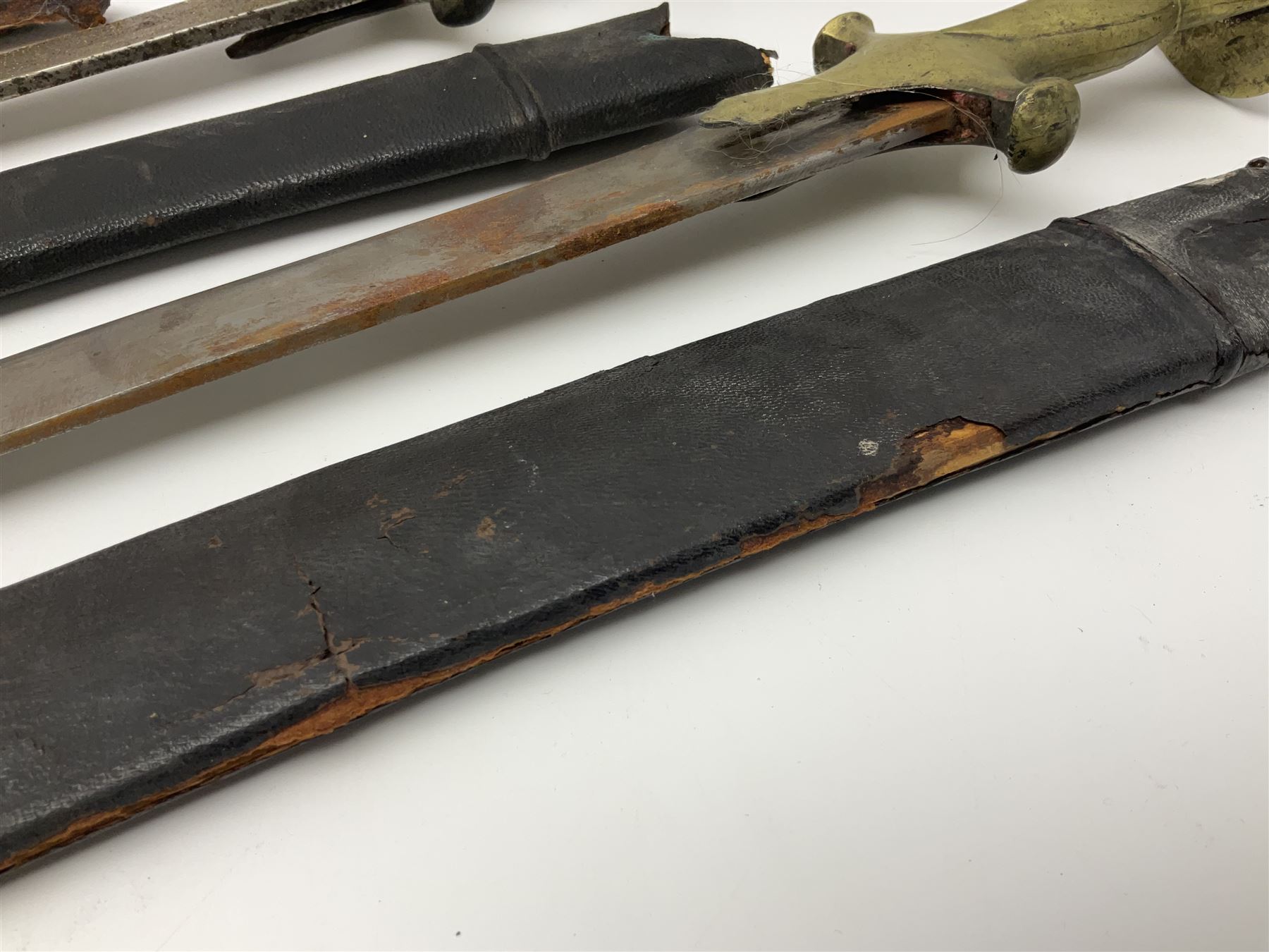 Four Indian tulwar swords; three with cast brass hilts and one with iron hilt; longest blade 81cm; all with scabbards (4)