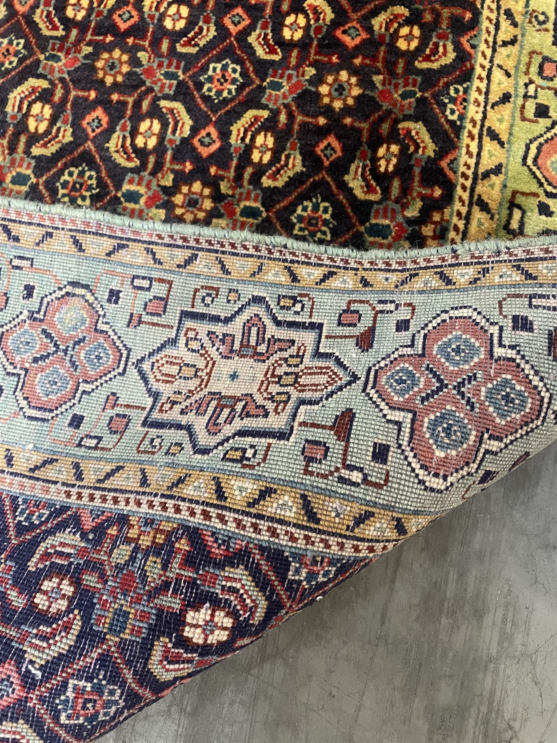 Persian Mahal rug, the blue ground field decorated with repeating Herati motifs, guarded pale ground border decorated with stylised panels