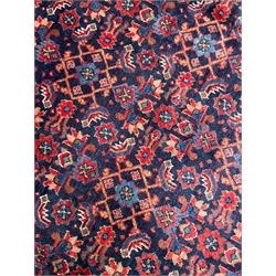 Persian indigo ground rug, the field decorated all over with floral Heratti motifs, crimson border with trailing stylised flower heads, within guard stripes