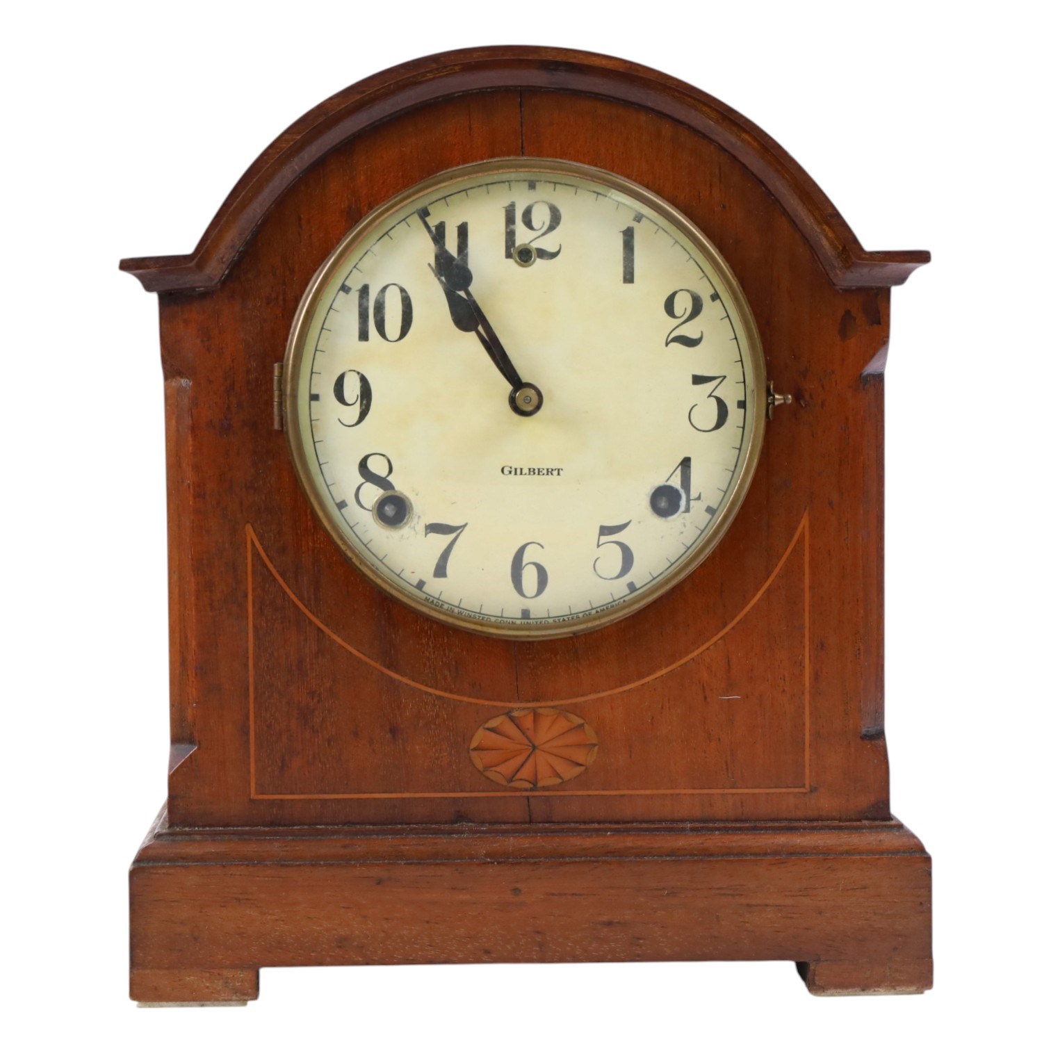 Gilbert Clock Company eight-day mahogany cased mantle clock, with a cream card dial, break arch top, upon a raised plinth, H28cm