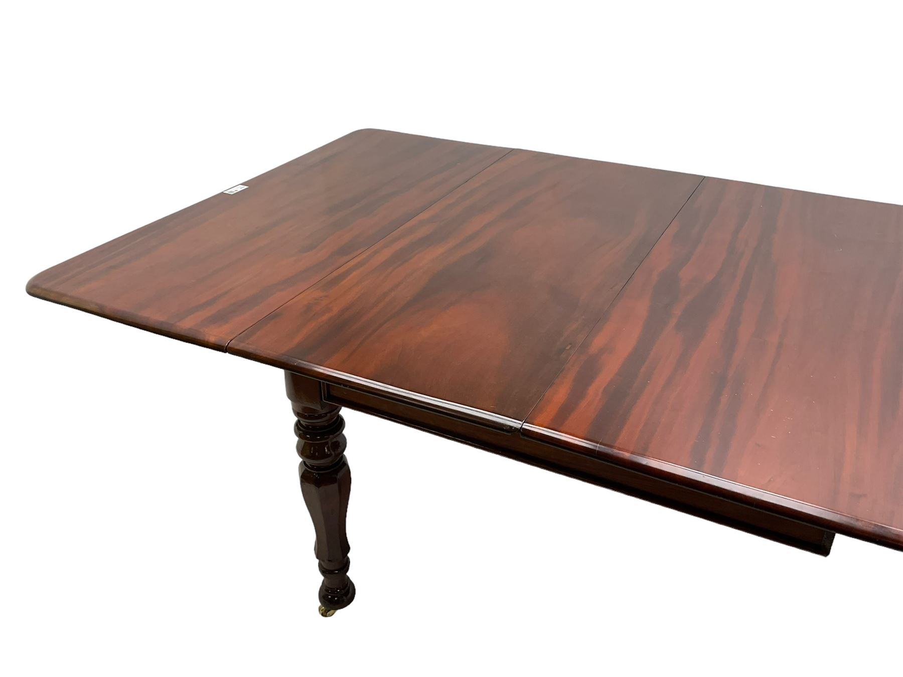 19th century mahogany extending dining table with three additional leaves, rectangular top with rounded corners, pull-out action, on turned and faceted supports with brass castors