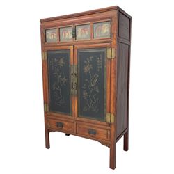 Late 19th century Chinese Qing dynasty red and black lacquered wood cabinet,  Fujianese province, upper cupboard enclosed by two doors with relief carved and gilt panels depicting figures behind glass, the large cupboard enclosed by two panelled doors carved with trailing foliate branches and birds, inscribed with Chinese characters, to the left ‘The red mountains are in the shape of Phoenixes and appear auspicious’ and to the right, ‘Wealth and honour are given by flowers and I hear the sound of the phoenix', fitted with two drawers, on square supports with carved brackets 