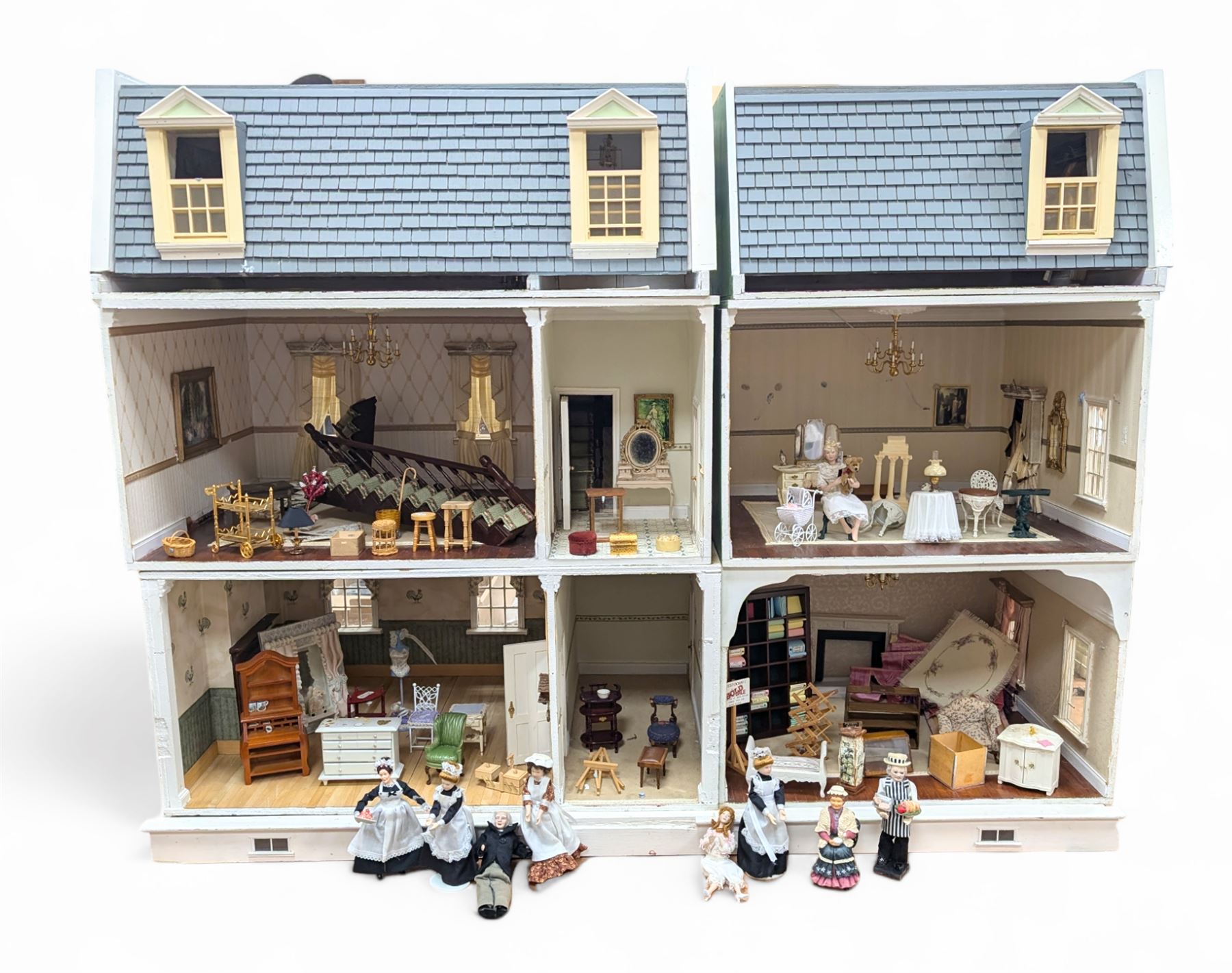 Two modern three storey dolls houses, each painted green with decorated interiors, both upon a single white wooden base, together with a large collection of dolls house furniture, accessories and figures 