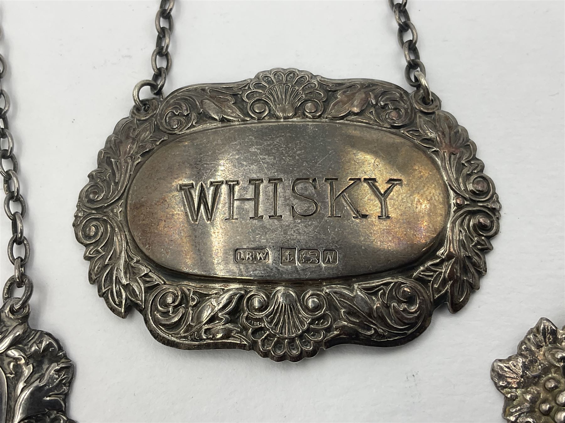 Five modern silver decanter labels, to include three similar Sherry and Brandy examples embossed with scrolls, two hallmarked C Robathan & Son, Birmingham 1989, and one hallmarked Laurence R Watson & Co, Birmingham 1987, together with a scotch example, hallmarked A Marston & Co, Birmingham 1970, and a larger sherry example, embossed with fruiting vines, hallmarked A Marston & Co, Birmingham 1993