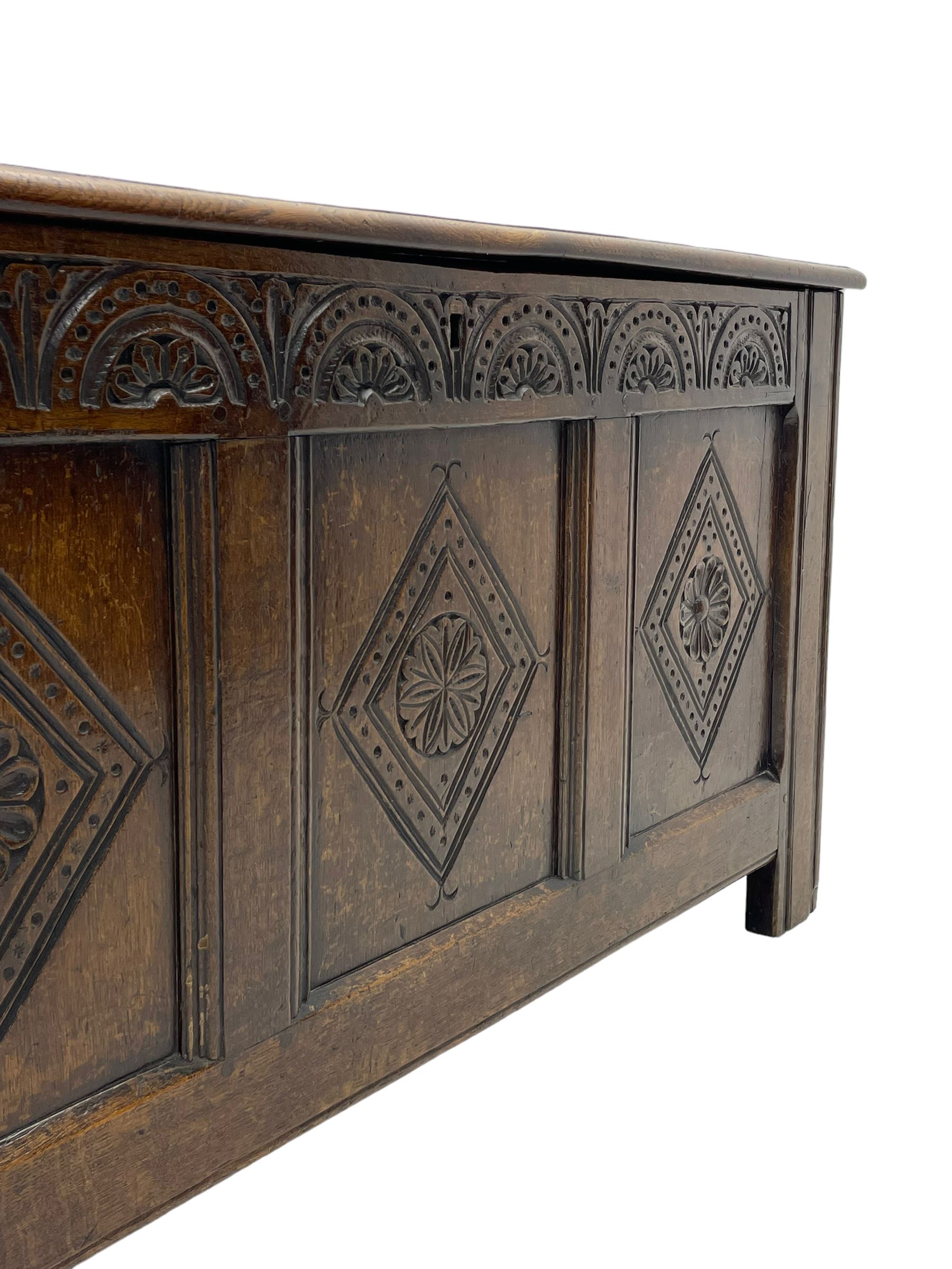 18th century oak coffer or chest, rectangular triple panelled hinged top with moulded edge enclosing main compartment and candle box, the frieze carved with repeating concentric lunettes and foliate patterns, the front fielded panels decorated with lozenges containing central flower heads, on stile supports