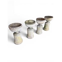 Four 20th century good quality weathered cast stone pedestal urns, circular lobed bowls with rope twist and lattice border, raised on squat base with fluted columns