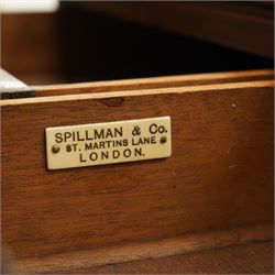 Regency inlaid mahogany and brass mounted library table, the rectangular top inset with gilt tooled burgundy leather writing surface, enclosed by  crossbanding and boxwood stringing with roundel corner motifs, above three cock-beaded frieze drawers to either side fitted with brass ring handles and brass escutcheons, the end friezes centred by applied brass foliate mounts, raised on twin reeded column supports over rectangular platform ends, united by a ring-turned stretcher, the reeded sabre legs terminating in brass caps and castors, one drawer bearing ivorine label 'Spillman & Co., St Martins Lane, London'