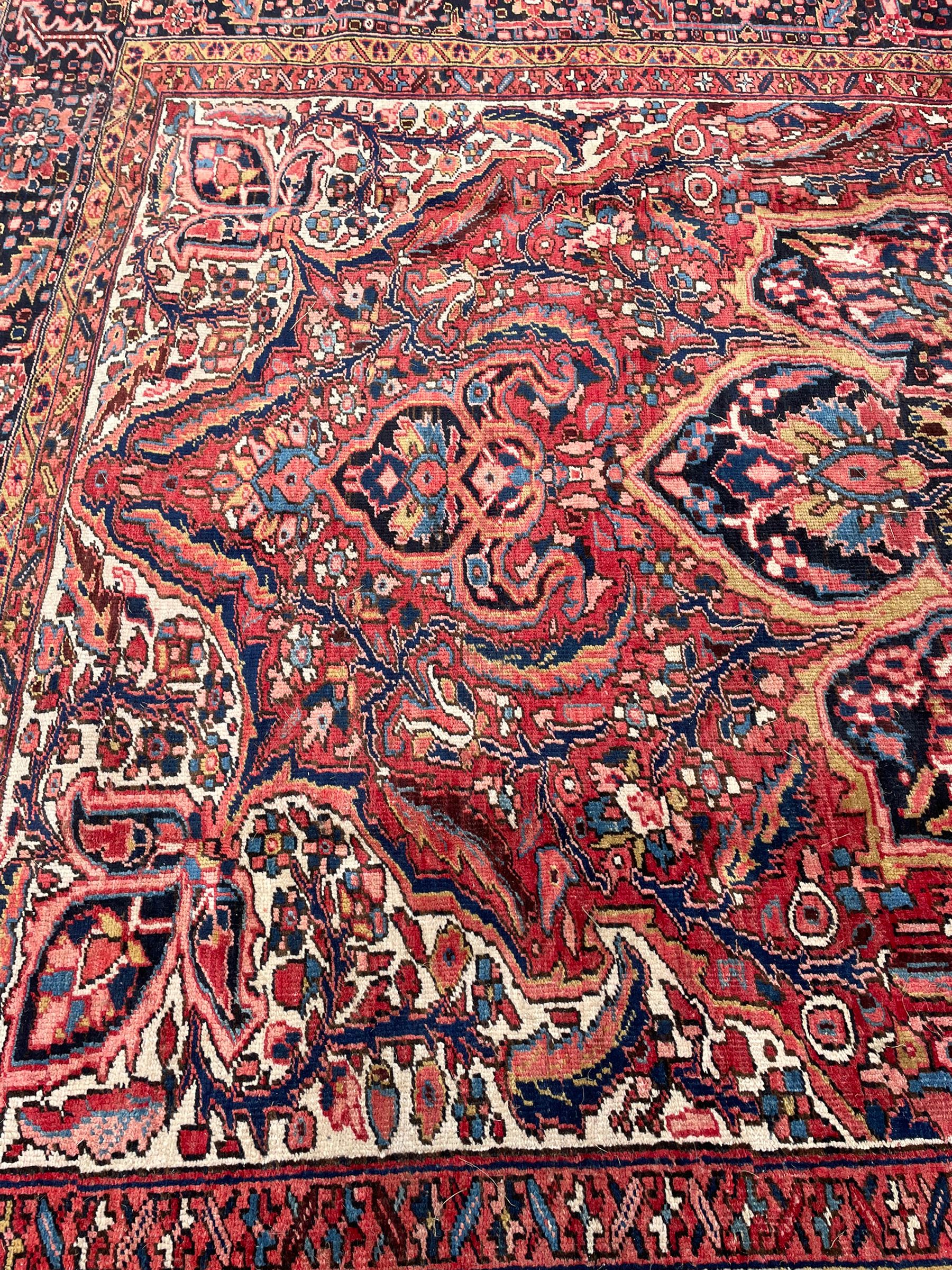 Antique Persian coral ground carpet, the large central floral pole medallion with extending foliate designs, the thick guarded indigo border with repeating flower heads and circles