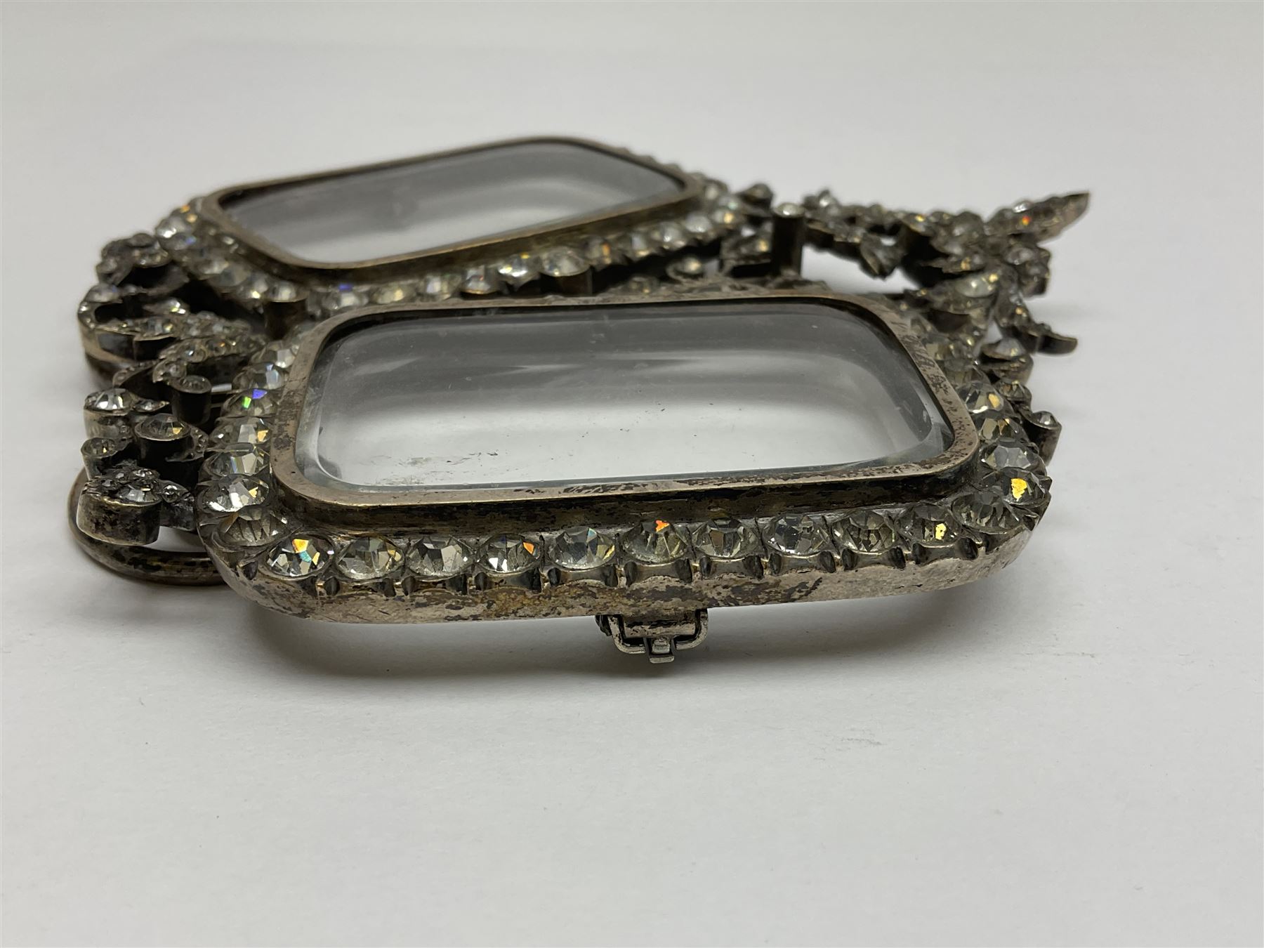 Early 19th century silver plated double photograph frame, each rounded rectangular aperture surrounded by a paste border, with ornate scroll feet and mantling also set with clear paste stones, with easel style support verso, H12cm