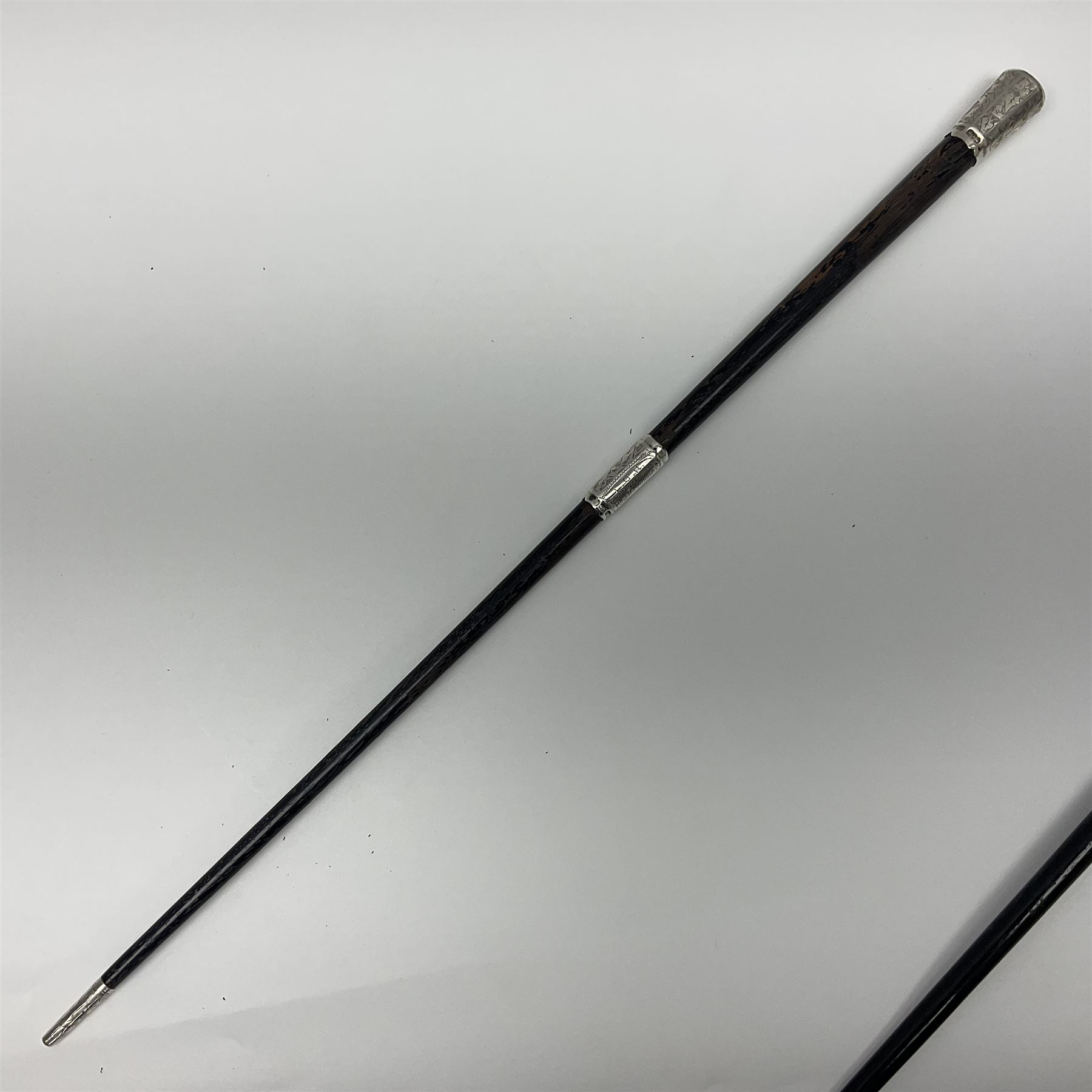 Two early 20th century conductor's ebonised batons each with three silver mounts; one hallmarked London 1915 with presentation plaque 'I.O.R. Presented to Mr. J.R. Maddock 4.1.17' L52cm; the other hallmarked Chester 1908 with vacant cartouche L51.5cm (2)