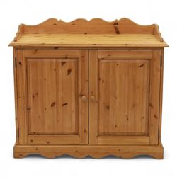 Contemporary pine cupboard, with raised shaped gallery over plain top, panelled double doors below with turned knob handles, shaped apron and plinth base