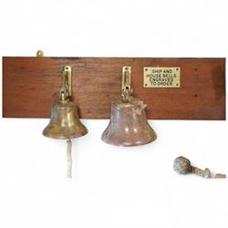 Set of three brass ship bells, each with wall bracket and two with rope pulls, mounted on a rectangular mahogany backboard with brass plaque inscribed ‘Ship and House Bells Engraved to Order’