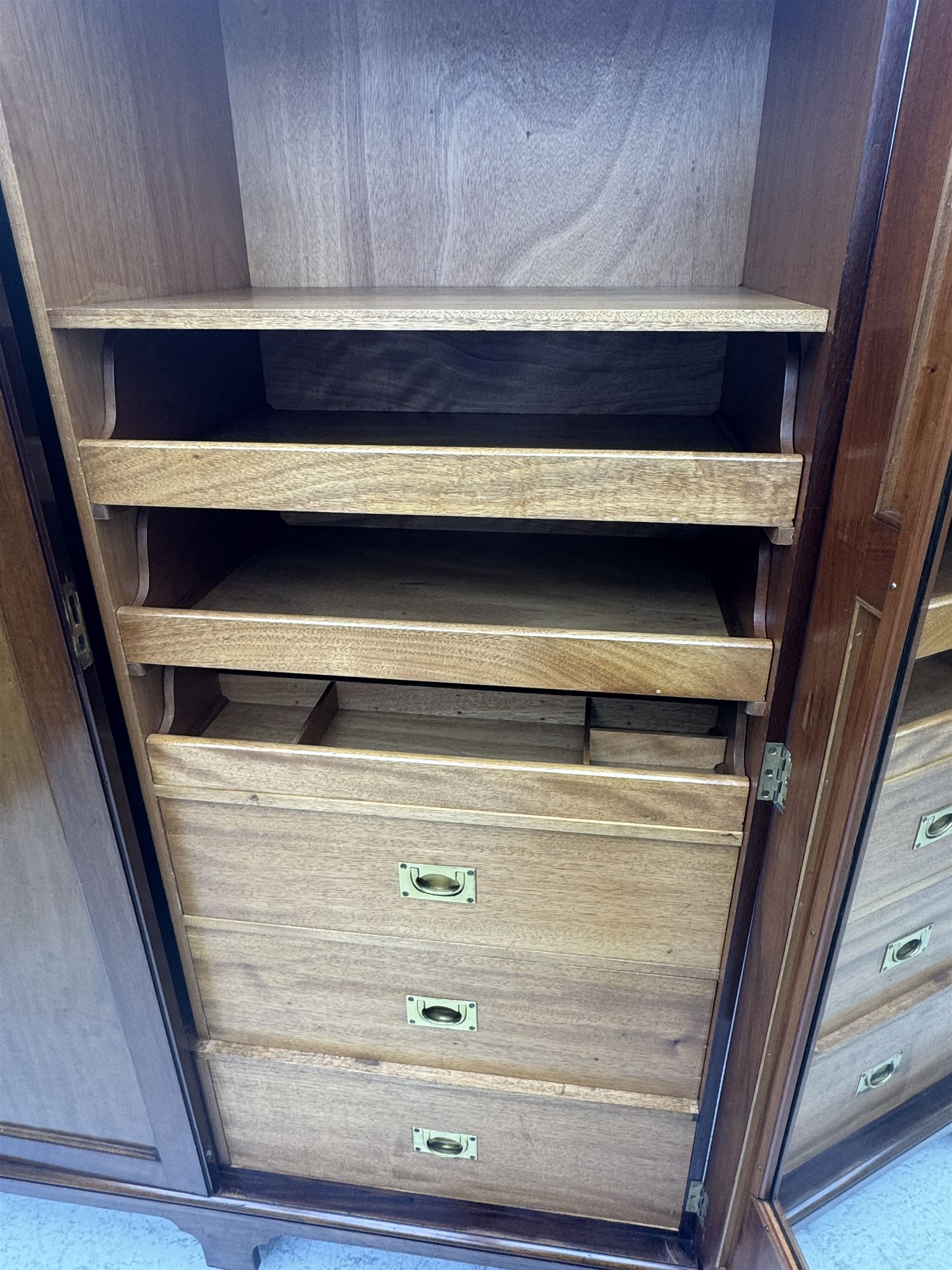 Wylie & Lochhead, Glasgow - early 20th century mahogany and satinwood double wardrobe, projecting cornice over panelled doors, interior fitted with mirrored door, shelves, drawers, hooks and hanging rail, raised on bracket supports with ceramic castors