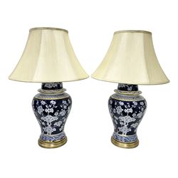 Pair of blue and white table lamps, each of baluster form, decorated with prunus blossom, within stylised borders, raised upon circular gilt base, excluding fittings H48cm