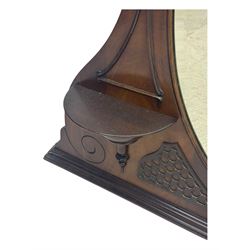 Early 20th century mahogany overmantel mirror, shaped broken pediment crest with open lattice panels, oval mirror plate flanked by scroll-carved bracket shelves

