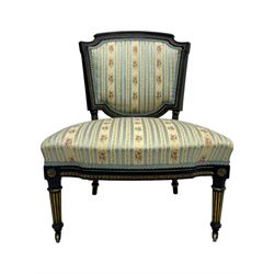 19th century French ebonised low chair, upholstered in floral striped fabric within a moulded frame with gilt line and foliate decoration, the seat of serpentine form, raised on turned fluted legs with toupie feet