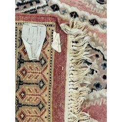 Persian design pale pink ground rug, the field divided into panels and decorated with Gul motifs, wide multi-band border with geometric patterns 