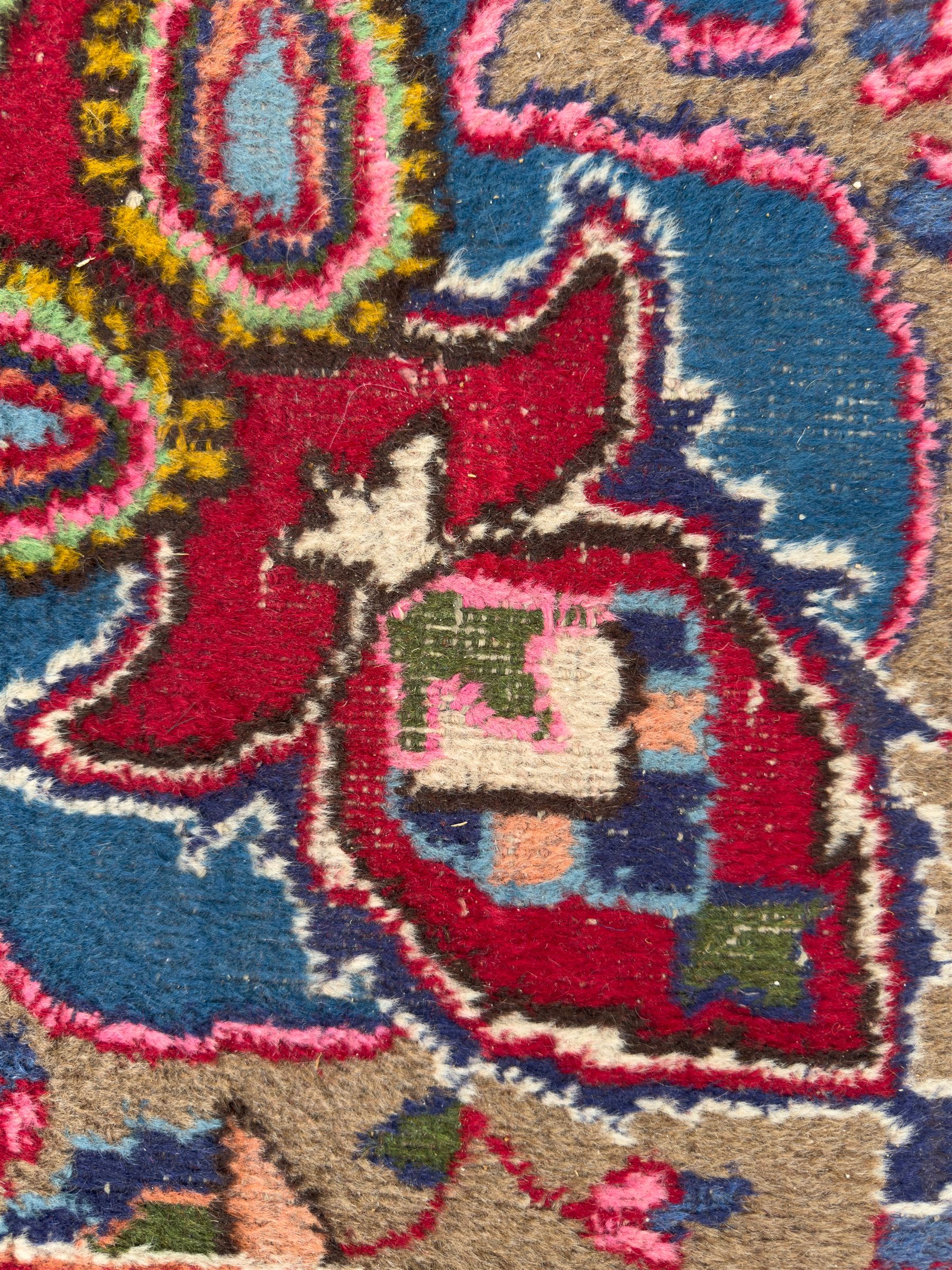 Pair of Persian wool rugs, each with rich red ground, one centred with a diamond-shaped medallion and navy spandrels within a floral field, the other with radiating floral medallion and scrolling foliate motifs, both enclosed by multiple borders with palmette and flowerhead designs, from the region of Kashan 291x376, 299 x 378 