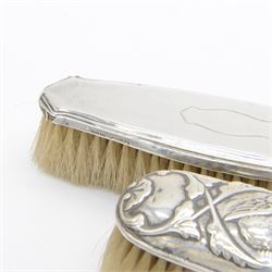 Group of silver mounted dressing table items, to include dwarf candlestick, with embossed ribbon decoration, comb holder, jar lid and six clothes brushes, all hallmarked 