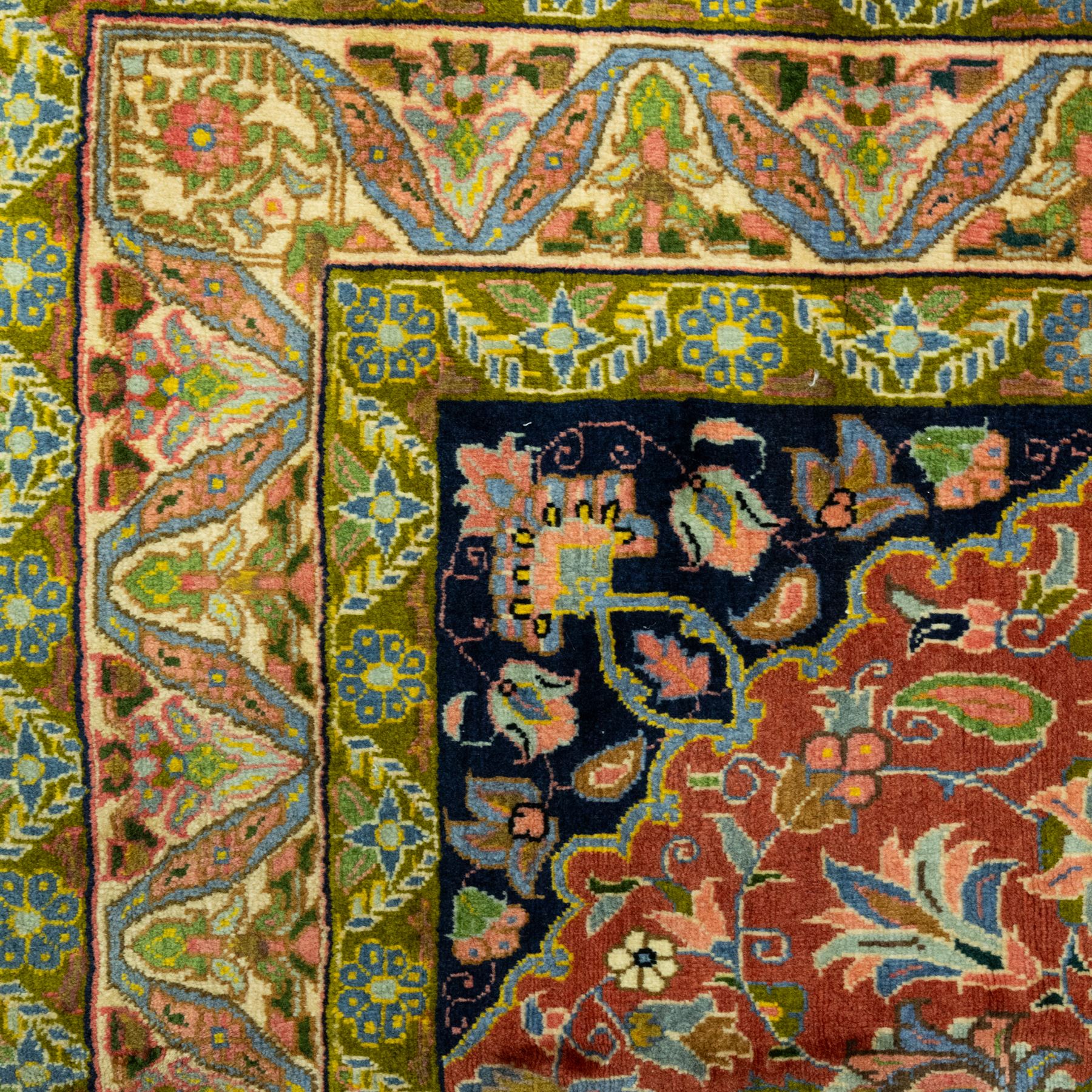 South Persian Sirjan hand-knotted carpet, terracotta ground, with a central shaped dark navy floral medallion with pendants, surrounded by scrolling foliate and floral motifs incorporating palmettes, rosettes and stylised vine work in blue, green and ivory tones, enclosed by dark navy spandrels and a wide green and ivory border with repeating palmettes and angular leaf motifs, flanked by patterned guard stripes, with cotton fringes