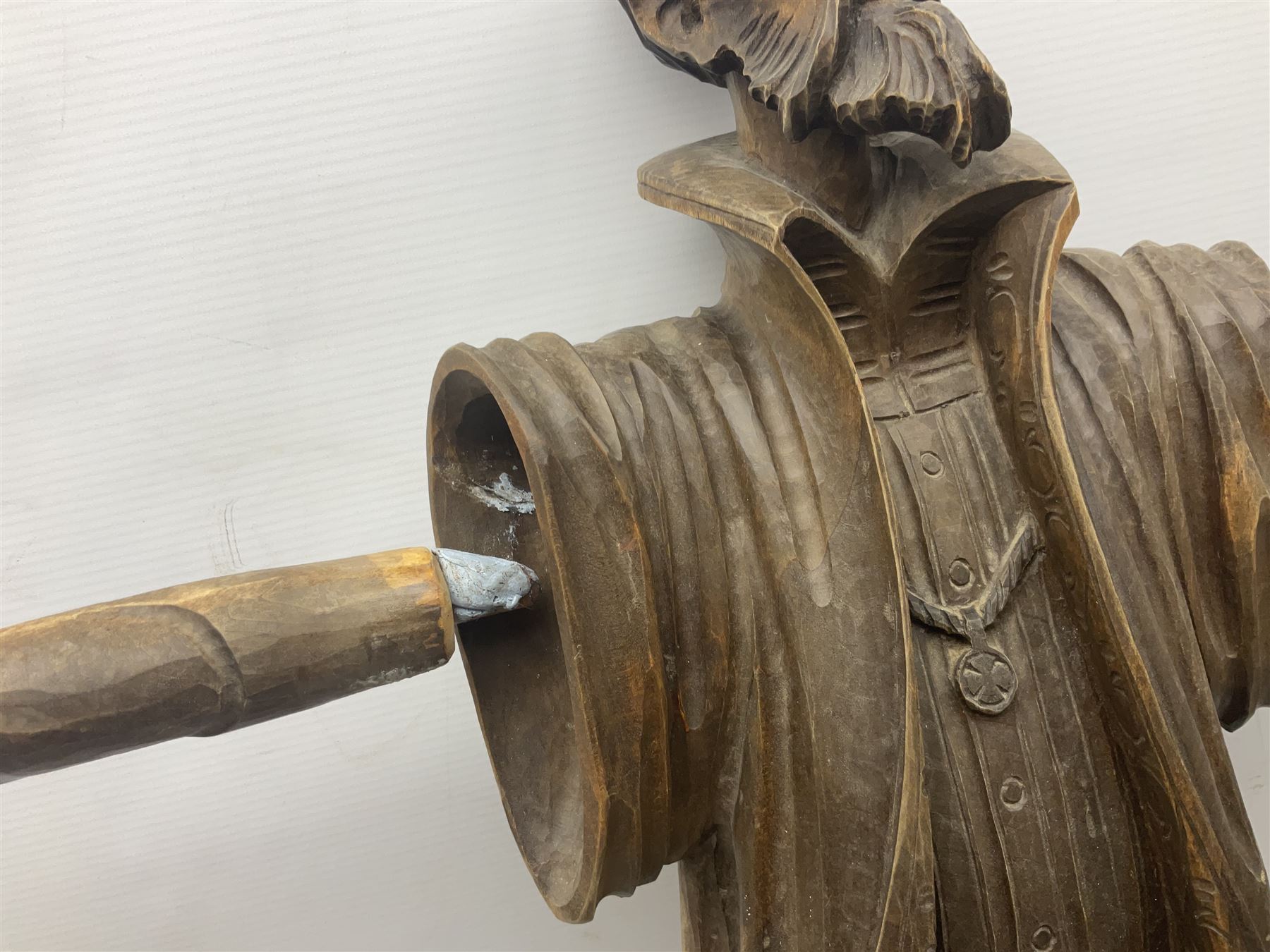 Spanish carved figure of Don Quixote, holding a book, base stamped 'Ouro, together with two spelter figures and one other