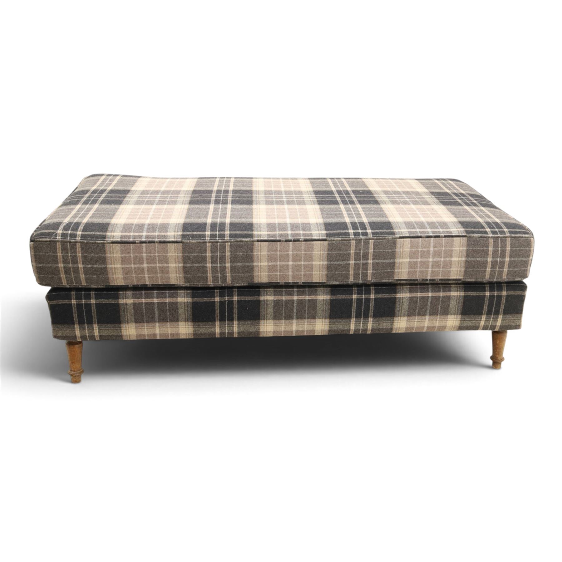 Large traditional design upholstered footstool, upholstered in checked fabric, with loose cushion, raised on a light turned supports 