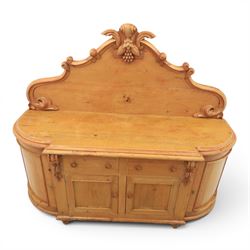 Victorian pine chiffonier, shaped moulded top with raised scroll carved back surmounted by carved fruit and foliate crest, fitted with two frieze drawers over two panelled cupboard doors, the outer cupboards of bowed form, carved foliate corbels, on plinth base