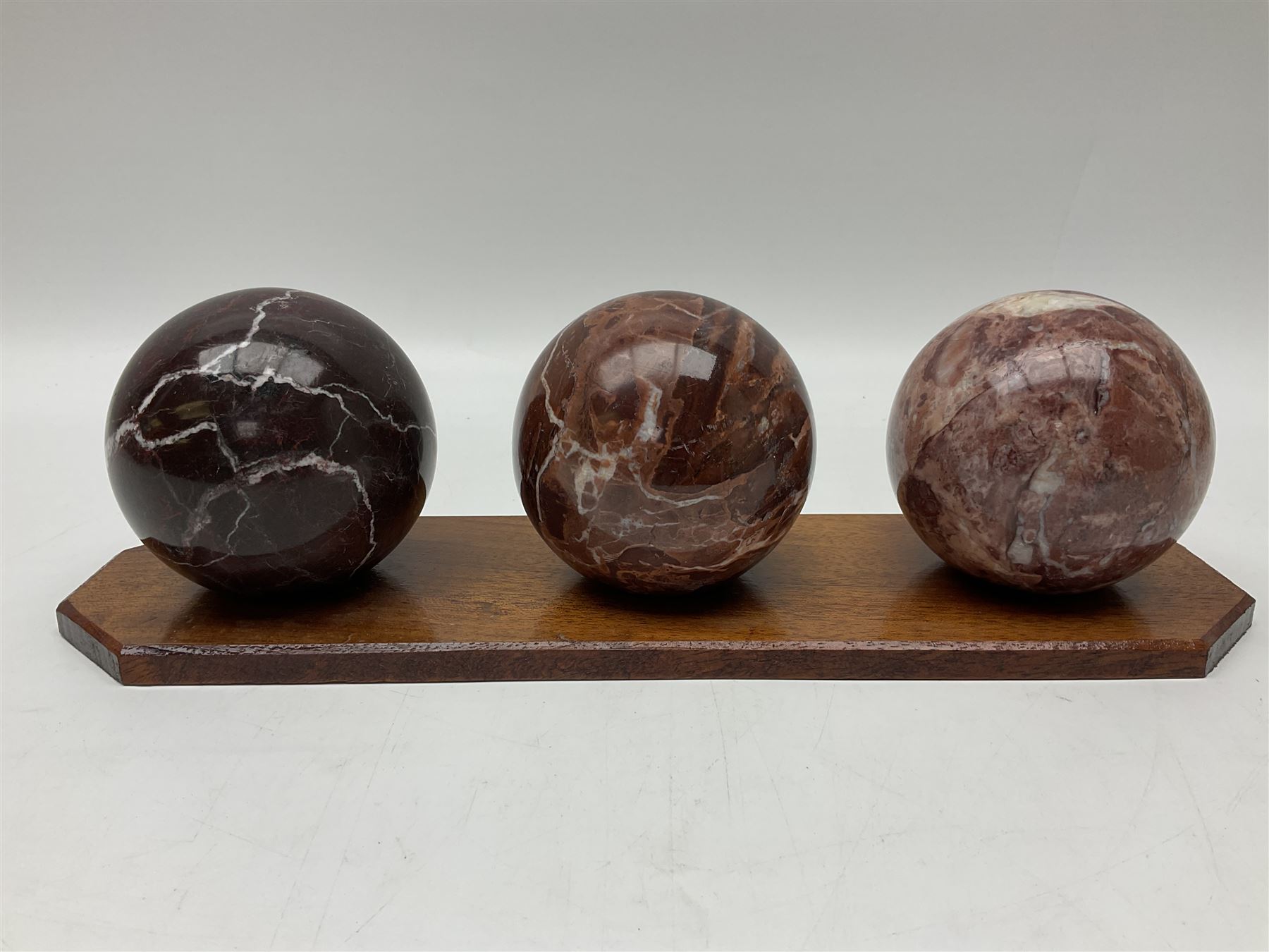 Set of three marble spheres on a elongated octagonal wooden base, H12cm