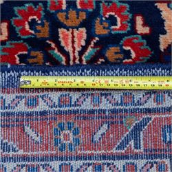 North West Persian runner, the indigo field decorated with repeating symmetrical floral sprays, rosettes and curling foliage in coral, ivory and pale blue tones, enclosed by a red ground trailing flowerhead border and narrow patterned guard bands 