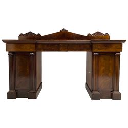 Early 19th century mahogany reverse break-front twin pedestal sideboard, raised back carved with cartouche and rosette detail with extending scrolling, fitted with two frieze drawers, the flanking panelled cupboards enclosing sliding trays and cellarette drawer