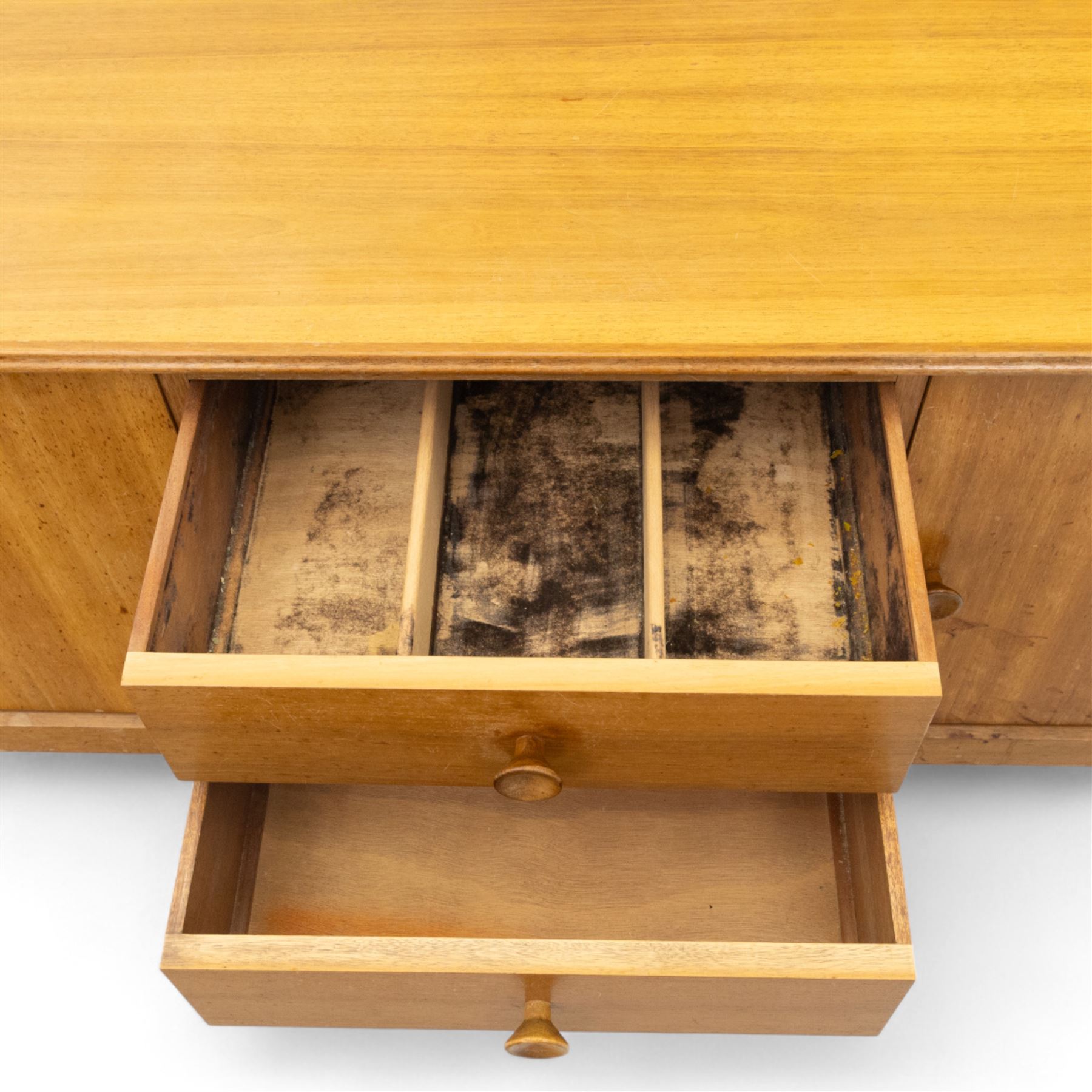 Gordon Russell - mid century modern teak sideboard, the rectangular top with rounded edges over twin cupboards and three central drawers, fitted with circular wooden pulls, on tapered supports, reflecting the firm’s commitment to simplicity and quality materials during the post-war design period