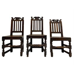 Set of three 18th century oak chairs, the cresting rail carved with C-scrolls and foliate, moulded upright and plain rails, plank seat, on turned and block supports with turned middle stretcher 