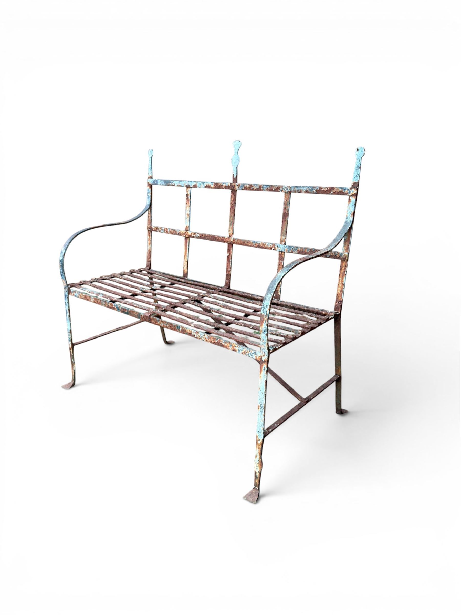 Regency period wrought iron strapwork garden bench, cresting rail with central Scottish thistle motif and flanking pediments, in distressed blue painted finish