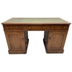 Victorian mahogany twin pedestal desk, rectangular top with green leather inset writing surface and moulded edge, fitted with three frieze drawers, the pedestals fitted with three drawers and three sliding trays, enclosed by arched fielded panel cupboard doors, on skirted base