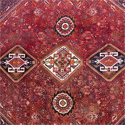 Qashqai wool carpet, red diamond-shaped field decorated with three stepped pole medallions, floral rosettes and scattered stylised motifs, within dark blue spandrels and multiple geometric guard borders