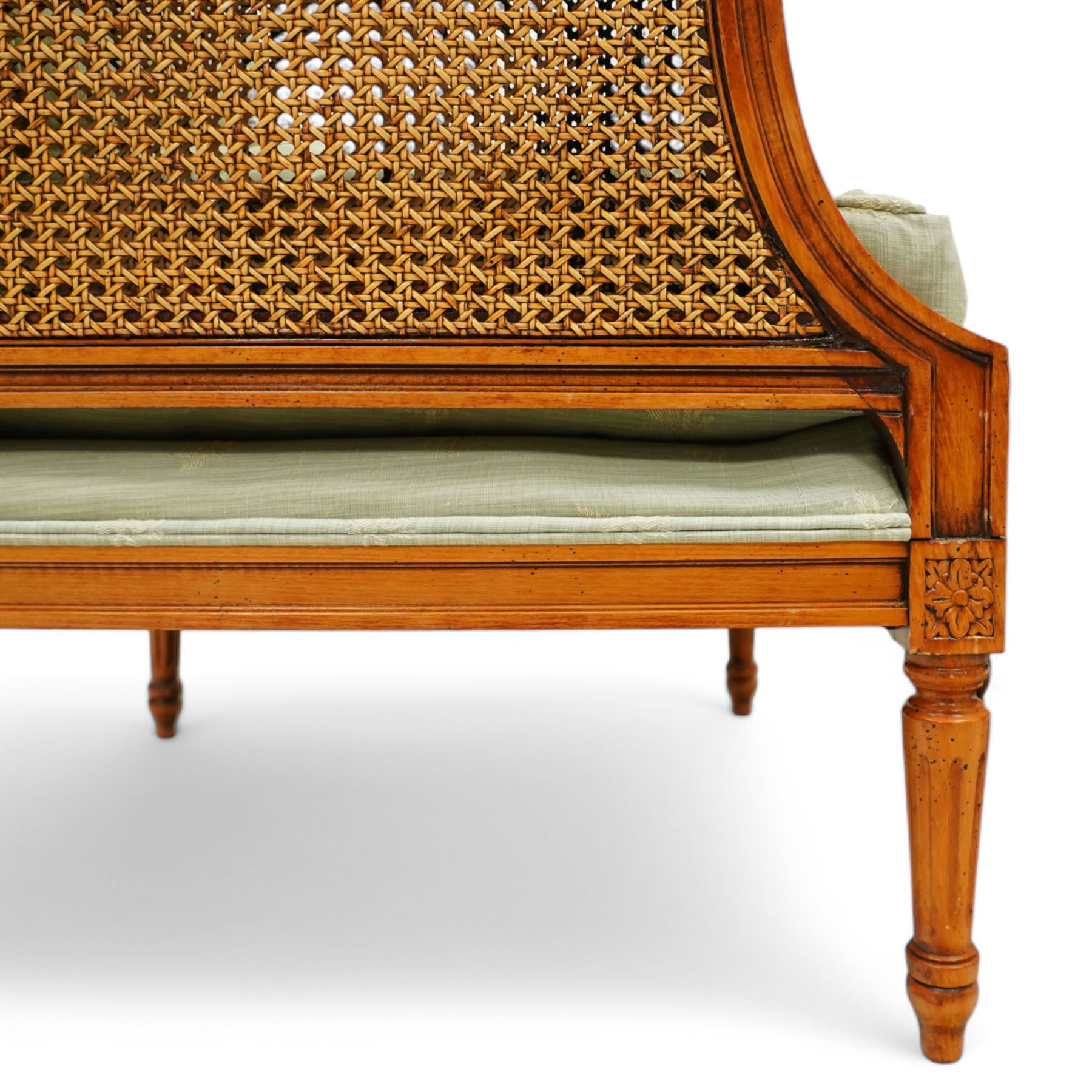 French Empire design varnished wood three piece lounge suite comprising of two cane armchairs and matching sofa, carved top rails with foliate terminals, cane side panels and padded scroll arms, upholstered in a green brocade with matching piping, on fluted legs